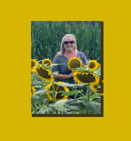 Heidi Durschlag standing in a field of sunflowers.